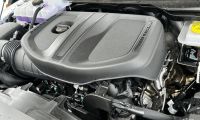 Close-up of a new Ram 1500's engine compartment, featuring a prominent engine cover marked "TURBO" and visible components. The scene conveys precision and modern engineering.