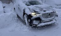 Mazda CX-90 covered in snow after winter storm, demonstrating AWD capability in deep snow
