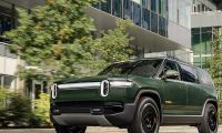 Rivian R1S electric SUV driving through a modern city street