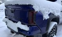 Toyota Tacoma pickup truck with tailgate frozen shut and covered in snow during winter