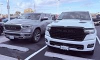 Two parked RAM 1500 trucks in a dealership lot on a clear day. One is silver and the other is white. Their bold grilles and large frames convey strength.