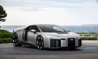 Silver Audi Nuvolari sports car parked near the coast with the ocean and cloudy sky behind it.  