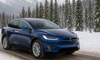 Blue Tesla Model X driving on a snow-covered mountain road