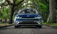 Blue Hyundai Ioniq 5 shown from the front on an oak-lined brick street with hanging moss.