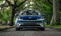 Blue Hyundai Ioniq 5 shown from the front on an oak-lined brick street with hanging moss.