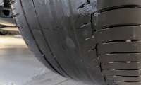 BMW tire with excessive uneven wear exposing a nearly bald inner shoulder despite tread remaining on the outer edge.