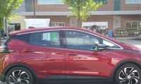 A Chevrolet Bolt in a briloiant red color is charging on a DC electric vehicle charger