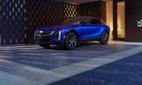 Blue Cadillac Lyriq parked under a modern carport next to a home EV charger.