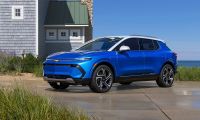 Blue Chevrolet Equinox EV parked near coastal home with ocean view