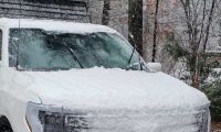 A Ford F-150 sits frozen in ice with its wipers in the up position