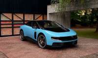 Blue Ferrari Luce shown from the front three-quarter angle outside a modern home with trees in the background.
