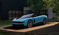 Blue Ferrari Luce parked outside a modern villa in a front three-quarter view.