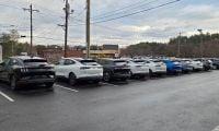 A long row of Ford Mustang Mach-E cars await buyers in November 2025 on a dealer's lot