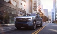 Ford F-150 Lightning electric pickup truck driving through a modern city street.