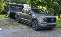 Ford F-150 parked with a Colorado travel trailer at a campsite