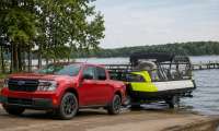 Red Ford Maverick pickup truck towing a Sea-Doo pontoon boat down a boat ramp into a lake