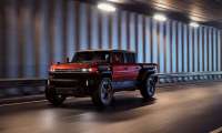 Red GMC Hummer HX truck concept driving through a tunnel in a front three-quarter action view.