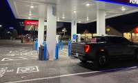 GMC Sierra EV parked at a GM Energy charging station at a Flying J travel center at night.