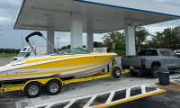 Gray GMC Sierra EV towing a yellow Regal boat while parked at a GM Energy charging station.