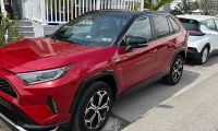 A Toyota RAV4 Prime sits in a warm Florida setting with a Chevy Bolt