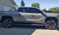 Gray GMC Sierra Denali pickup shown from the side while parked in a driveway.