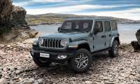Front three-quarter view of a Jeep Wrangler Unlimited 4xe on rocky terrain by the coast.