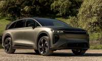 Lucid Gravity electric SUV shown from the front three-quarter angle on a gravel road near trees.
