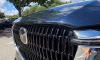 Close-up of scratches and paint damage on the front grille and hood edge of a Mazda SUV.