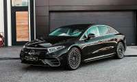 Black Mercedes-Benz EQS electric sedan parked in front of a modern garage.