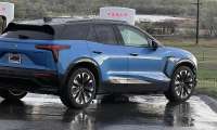 Michael's blue Chevrolet Blazer EV parked at a Tesla Supercharger station on a rainy day during a road trip.