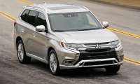 Silver Mitsubishi Outlander plug-in hybrid driving on a curving road.