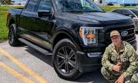 RJ posing beside his black 2022 Ford F-150 PowerBoost in military uniform.