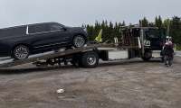 Saleh's 2023 GMC Yukon Denali Ultimate being loaded onto a flatbed tow truck on the roadside after experiencing a mechanical issue, with a person standing nearby during the recovery process.