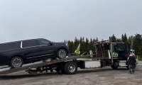 Saleh's 2023 GMC Yukon Denali Ultimate being loaded onto a flatbed tow truck on the roadside after experiencing a mechanical issue, with a person standing nearby during the recovery process.