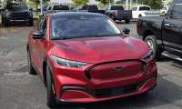 Shawn’s red Ford Mustang Mach-E parked outside a dealership, highlighting its sporty EV styling.