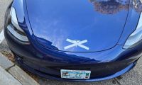 A Tesla is shown with its logo crossed out by the vehicle's owner