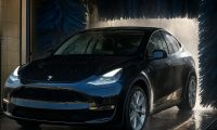 A Tesla Model Y exits a car wash tunnel looking sparkly clean