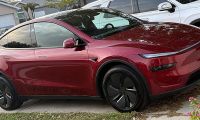 Red Tesla Model Y parked in residential driveway with suburban homes