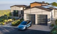 Tesla Model X parked in a modern hillside home driveway with solar panels and home EV charging station