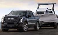 The exterior shot of the 2027 GMC Sierra 1500 Denali Ultimate in Dark Ridge Metallic towing a boat.