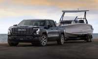 The exterior shot of the 2027 GMC Sierra 1500 Denali Ultimate in Dark Ridge Metallic towing a boat.