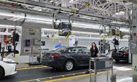 A Toyota worker smiles as a newly-produced Toyota rolls off an American assembly line