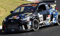 Black Toyota GR Yaris race car with TG-RR racing livery cornering on a racetrack, front three-quarter view