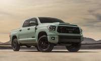 Sage green Toyota Tundra TRD Pro pickup truck parked on a desert lakebed, front three-quarter view with dramatic sky