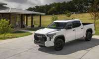 White Toyota Tundra TRD Pro pickup truck parked in the driveway of a ranch-style house with a covered porch