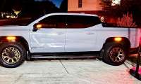 White GMC Sierra Denali parked at night in a driveway beside a basketball hoop with marker lights on.