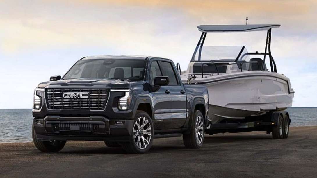 The exterior shot of the 2027 GMC Sierra 1500 Denali Ultimate in Dark Ridge Metallic towing a boat.