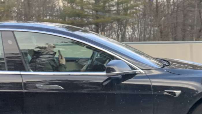 Image of male Tesla driver using hand-held phone by John Goreham