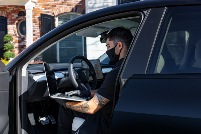 Image of man in vehicle with laptop courtesy of Tesla, Inc media page.