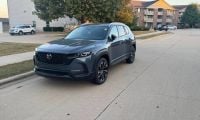 2026 Mazda CX-50, Front 3_4 Quarters, Silver 2026 Mazda CX-50, in metallic blue, side profile view, featuring black trim, distinctive two-tone alloy wheels, parked outside dealership.
